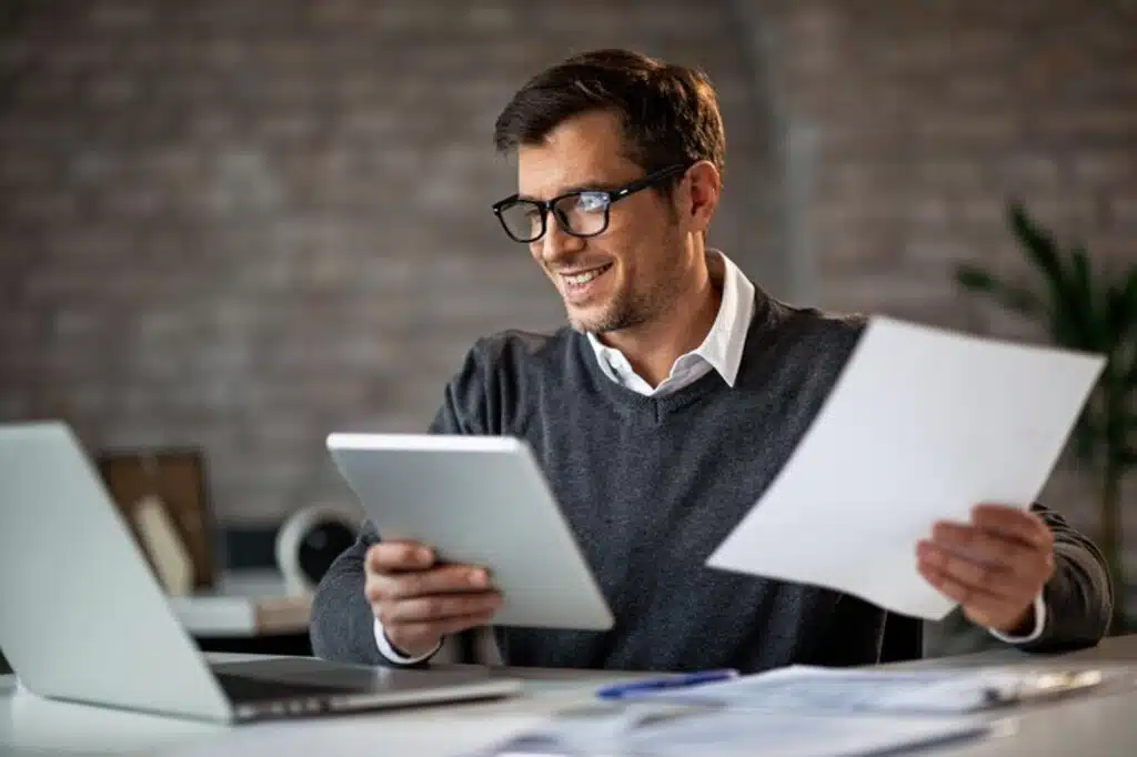 Empresário em frente a notebook com papeis