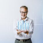 Homem de negócios sorridente analisa crescimento financeiro representado por gráfico de barras digitais holográficas, simbolizando sucesso em investimentos e estratégias empresariais.