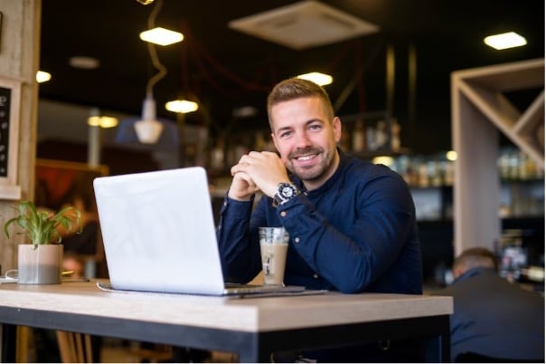 Empresário na mesa com o notebook aberto.